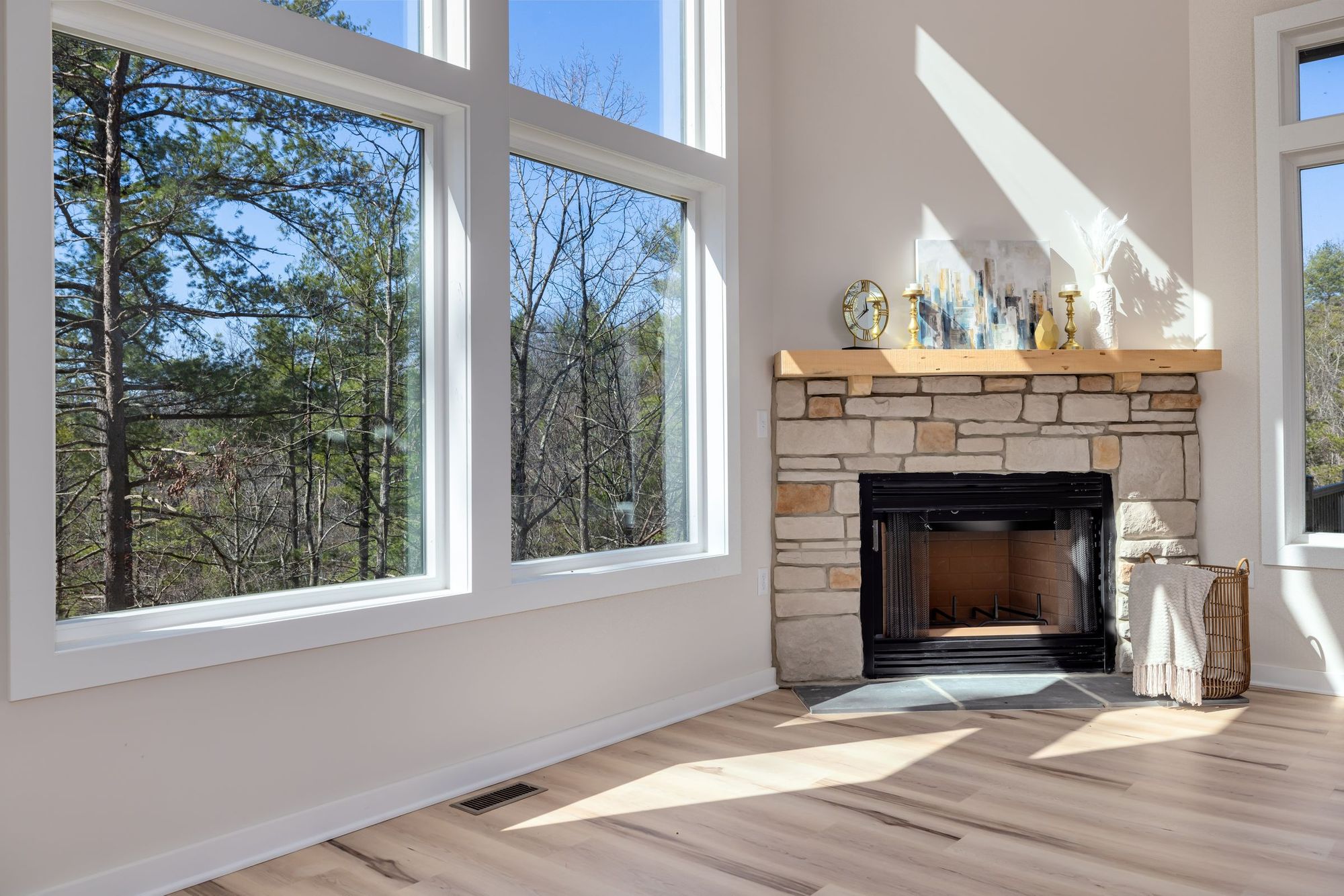 Room with a stone fireplace and windows onto the woods
