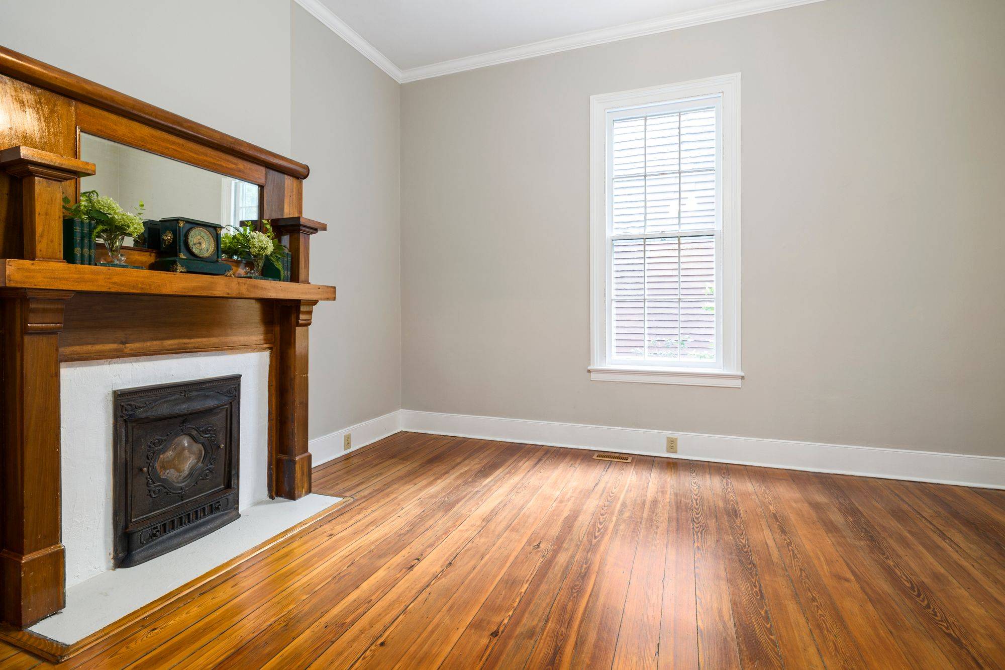 Empty room with a classic wood mantel and pine floors
