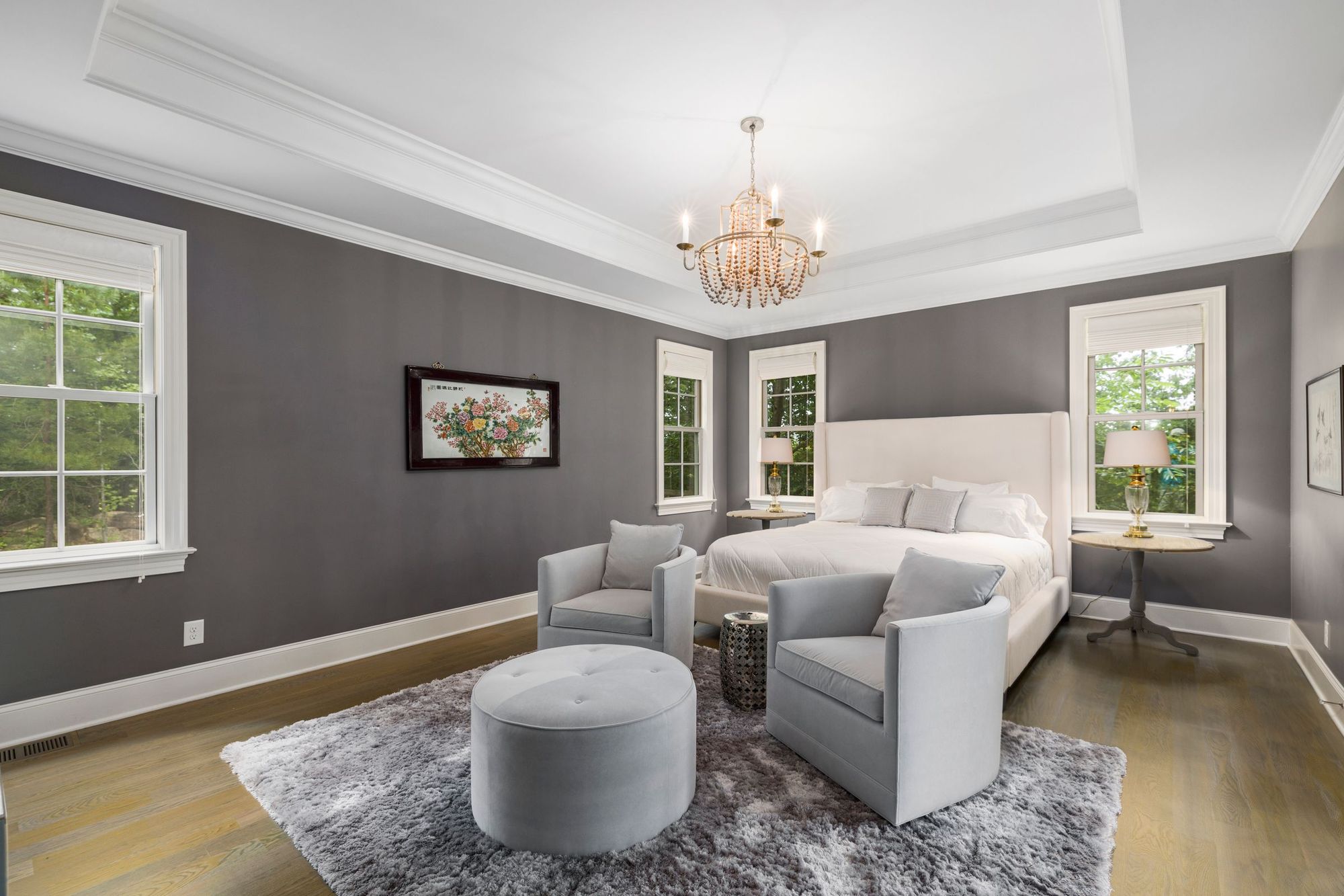 Primary suite with a crystal chandelier and tall windows onto the woods